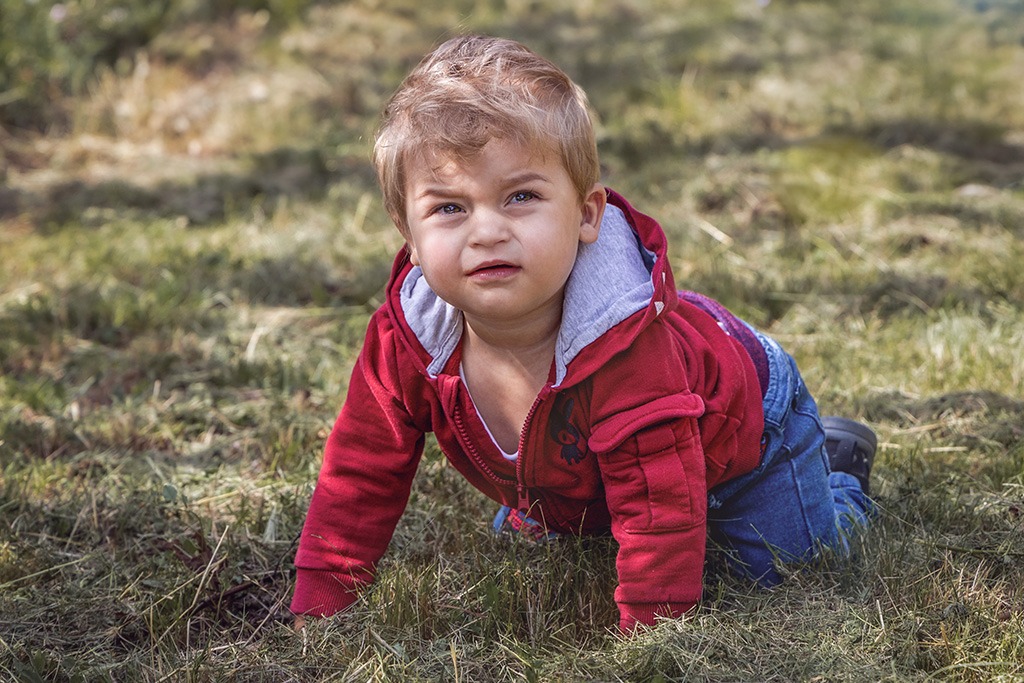 Fotografie chlapce lezoucích po trávě