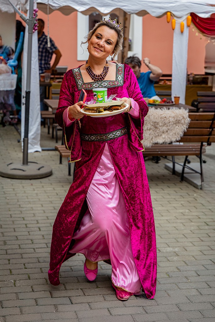 Eventová fotografie ženy v růžových šatech, jak nese občerstvení